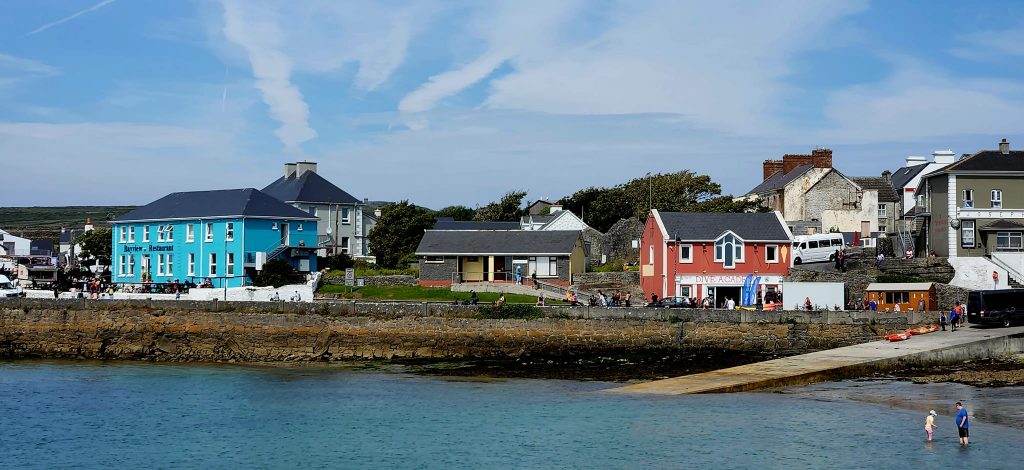 Sight of Inishmore with colorful buildings, bright blue sky, ocean side after arriving by ferry. 
