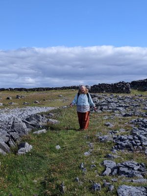The author, Sarah, walking down a grassy field that is also full of rough, jagged limestone. Pilgrimage to Ireland.